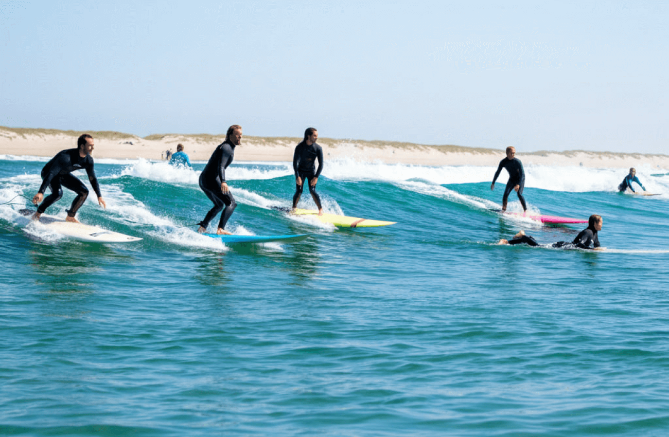 A group of people with an instructor in the water as they learn to surf