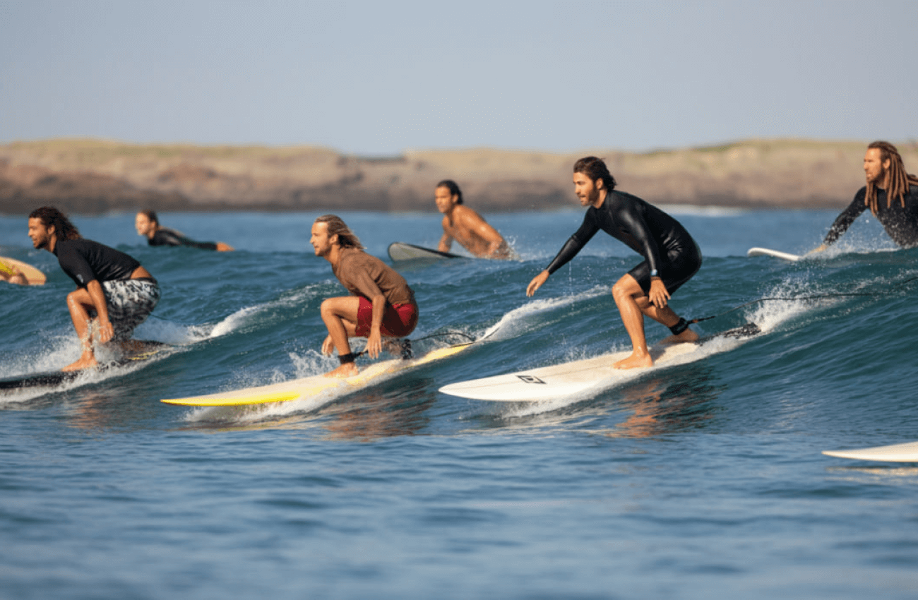 A group of surf beginners practicing in the shallow water with their boards
