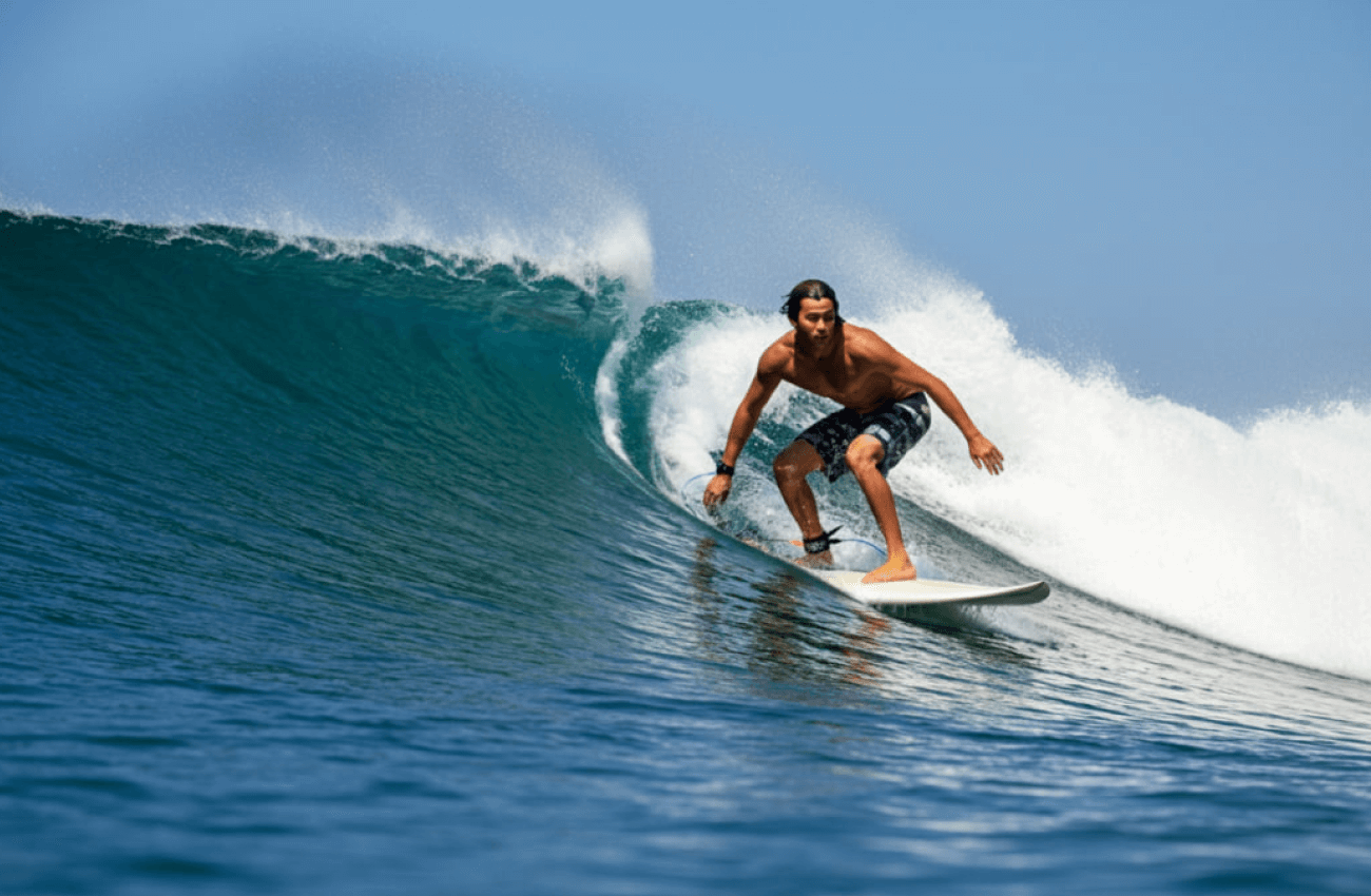 A solo surfer catching a wave on a sunny day while surfing in Phuket
