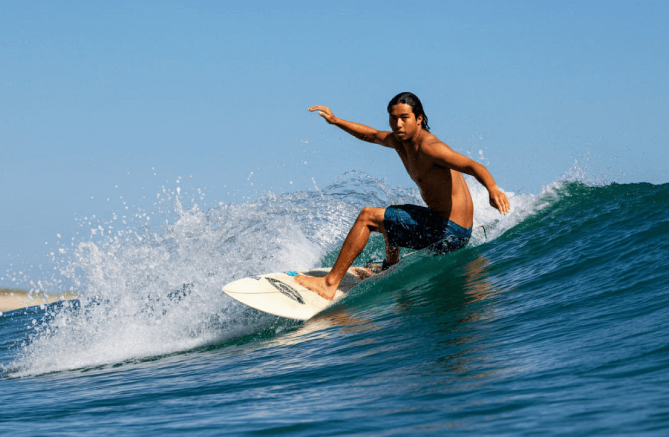 A man successfully riding a wave during his beginner surf lessons