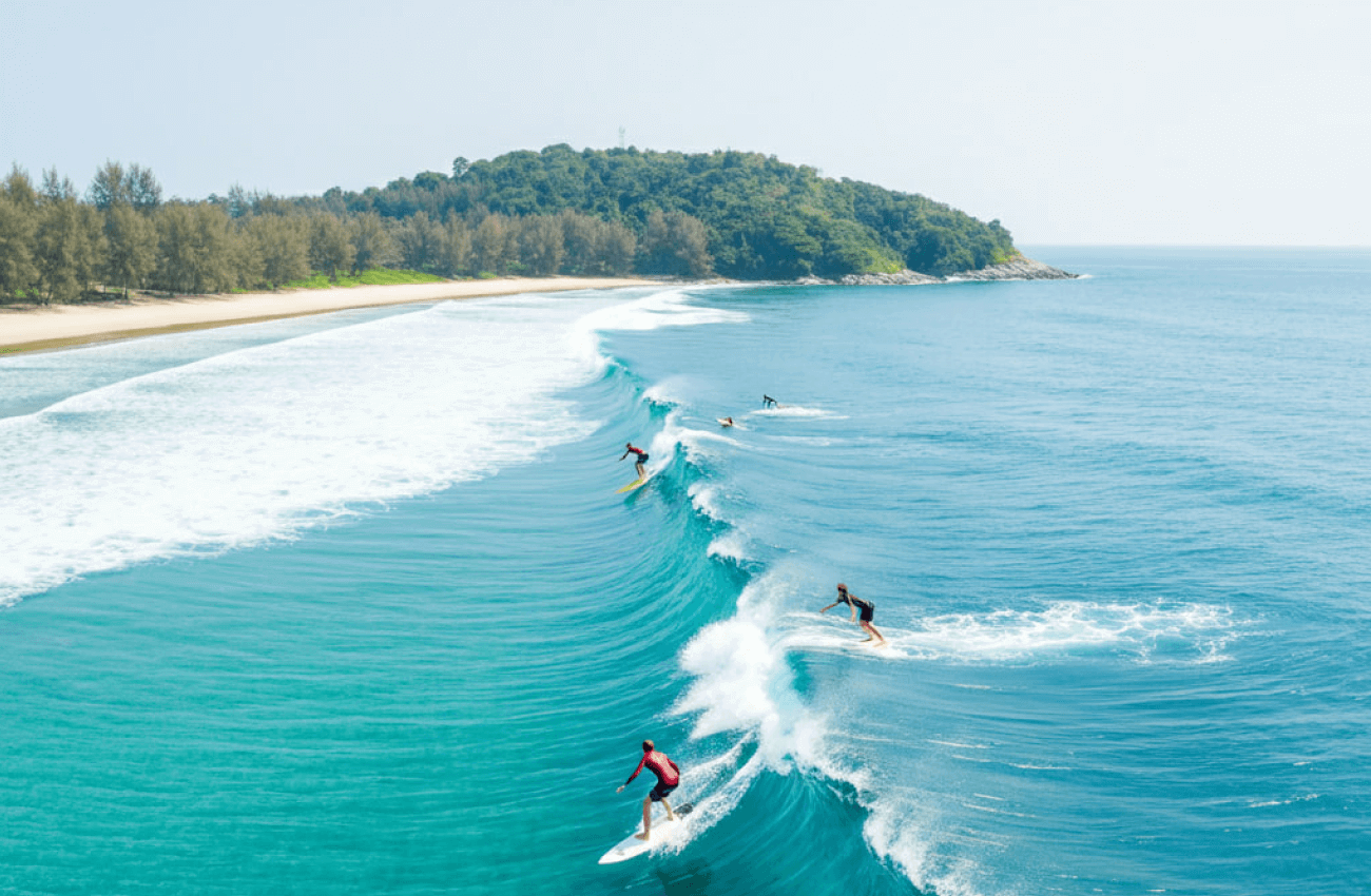 A group of people learning how to surf begin at Phuket with an instructor