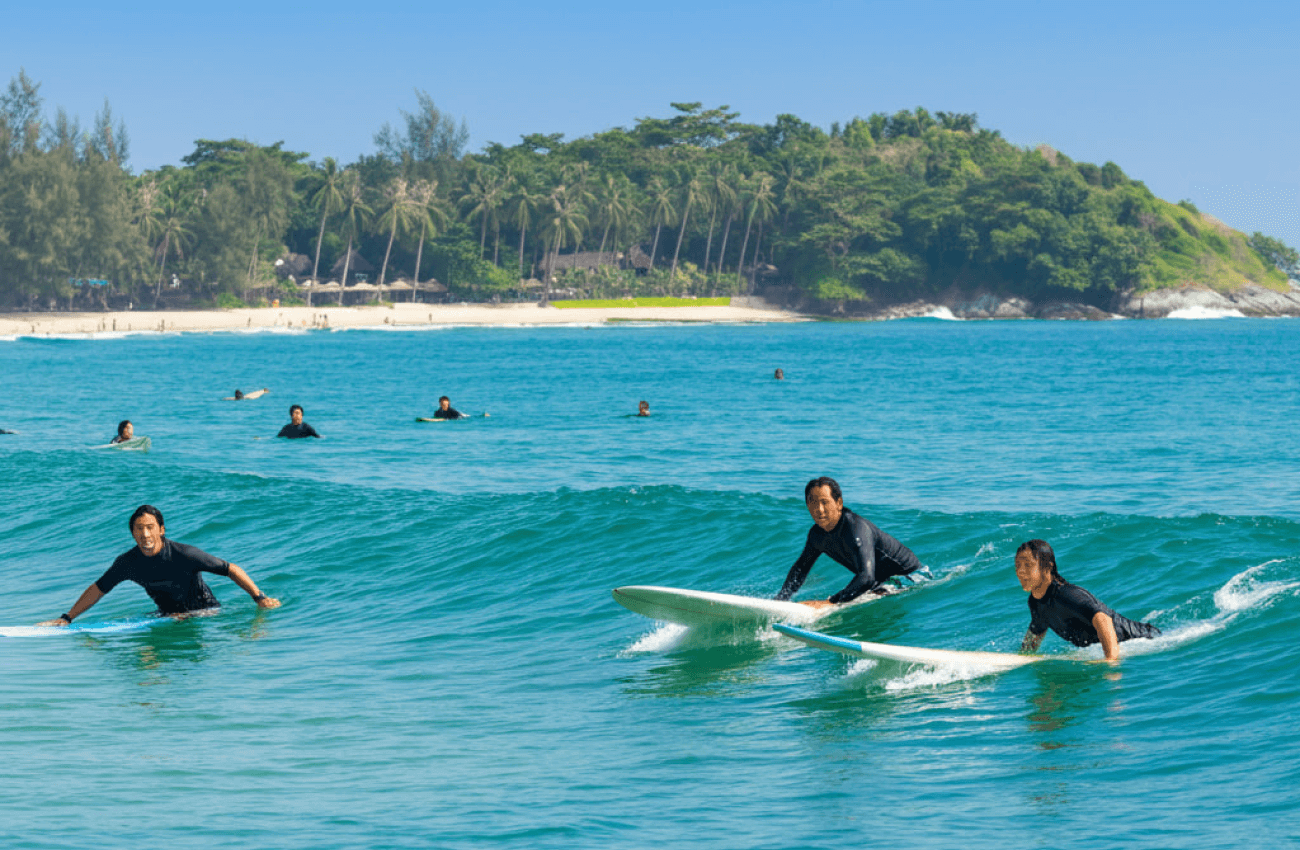 A group of beginners surfing for the first time with the help of a coach